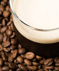 Serving of nitro cold brew coffee surrounded by coffee beans