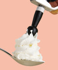 A CreamRight whipped cream dispenser adding whipped cream to a spoon